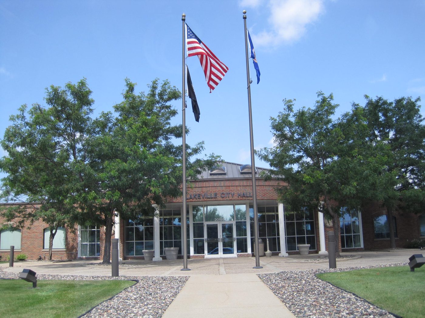 Lakeville City Hall entrance with flags and a concrete walkway