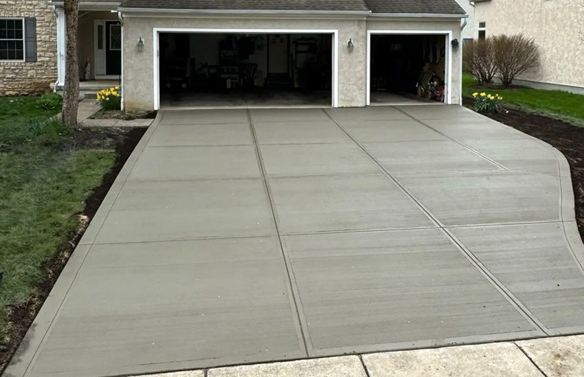 New construction concrete driveway with curved edge and boulder wall in Elk River, MN