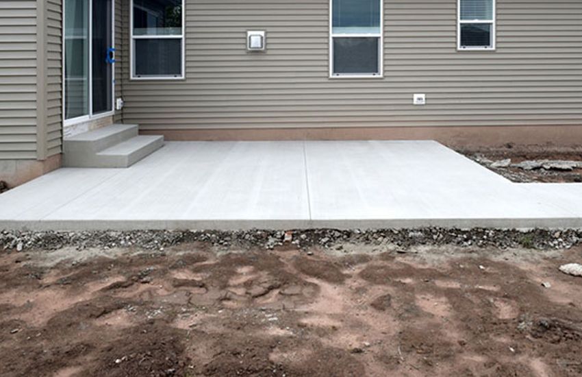 Curved exposed aggregate front entry walkway to a stone-columned entrance